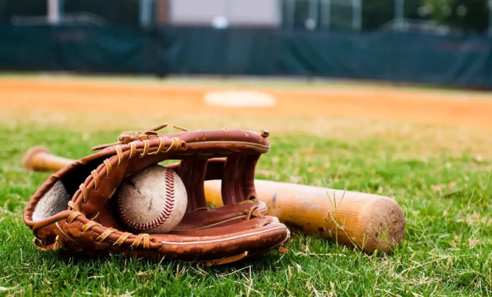 Bate y guante de béisbol en el césped de un campo de béisbol