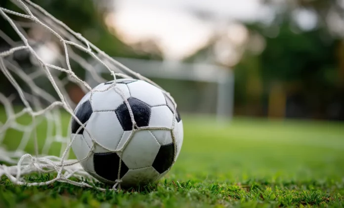 Balón de fútbol entrando en un arco al fondo de la red en una cancha